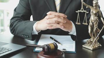 Business and lawyers discussing contract papers with brass scale on desk in office. Law, legal services, advice, justice and law concept picture with film grain effect video