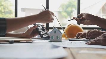 costruzione e struttura concetto di ingegnere o architetto incontro per progetto Lavorando con compagno e ingegneria utensili su modello edificio e planimetria nel Lavorando luogo, contrarre per tutti e due aziende. video