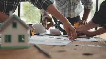 costruzione e struttura concetto di ingegnere o architetto incontro per progetto Lavorando con compagno e ingegneria utensili su modello edificio e planimetria nel Lavorando luogo, contrarre per tutti e due aziende. video