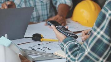 costruzione e struttura concetto di ingegnere o architetto incontro per progetto Lavorando con compagno e ingegneria utensili su modello edificio e planimetria nel Lavorando luogo, contrarre per tutti e due aziende. video