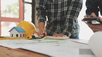 costruzione e struttura concetto di ingegnere o architetto incontro per progetto Lavorando con compagno e ingegneria utensili su modello edificio e planimetria nel Lavorando luogo, contrarre per tutti e due aziende. video