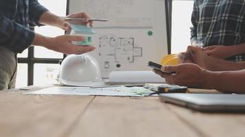 costruzione e struttura concetto di ingegnere o architetto incontro per progetto Lavorando con compagno e ingegneria utensili su modello edificio e planimetria nel Lavorando luogo, contrarre per tutti e due aziende. video