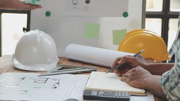 costruzione e struttura concetto di ingegnere o architetto incontro per progetto Lavorando con compagno e ingegneria utensili su modello edificio e planimetria nel Lavorando luogo, contrarre per tutti e due aziende. video