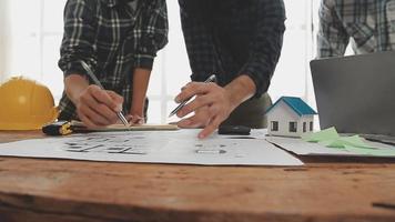 costruzione e struttura concetto di ingegnere o architetto incontro per progetto Lavorando con compagno e ingegneria utensili su modello edificio e planimetria nel Lavorando luogo, contrarre per tutti e due aziende. video