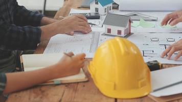 costruzione e struttura concetto di ingegnere o architetto incontro per progetto Lavorando con compagno e ingegneria utensili su modello edificio e planimetria nel Lavorando luogo, contrarre per tutti e due aziende. video