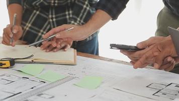 costruzione e struttura concetto di ingegnere o architetto incontro per progetto Lavorando con compagno e ingegneria utensili su modello edificio e planimetria nel Lavorando luogo, contrarre per tutti e due aziende. video