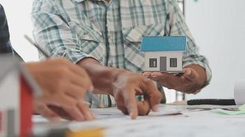 costruzione e struttura concetto di ingegnere o architetto incontro per progetto Lavorando con compagno e ingegneria utensili su modello edificio e planimetria nel Lavorando luogo, contrarre per tutti e due aziende. video