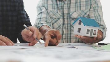 costruzione e struttura concetto di ingegnere o architetto incontro per progetto Lavorando con compagno e ingegneria utensili su modello edificio e planimetria nel Lavorando luogo, contrarre per tutti e due aziende. video