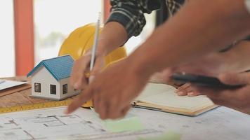 costruzione e struttura concetto di ingegnere o architetto incontro per progetto Lavorando con compagno e ingegneria utensili su modello edificio e planimetria nel Lavorando luogo, contrarre per tutti e due aziende. video