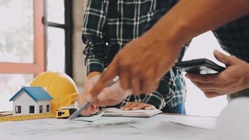 construcción y estructura concepto de ingeniero trabajando dibujo en Plano reunión para proyecto trabajando con compañero en modelo edificio y Ingenieria herramientas en trabajando sitio, construcción concepto video