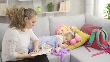 le mère raconte une récit à sa enfant et le enfant chutes endormi. le mère lit une Fée conte à le somnolent fille et le fille essaie à dormir. video