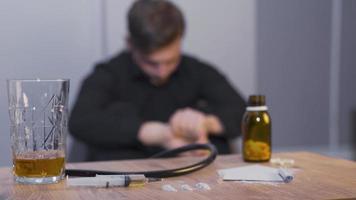 Substance addict man having crisis. Cocaine and heroin on the table and man having a seizure in the background. video