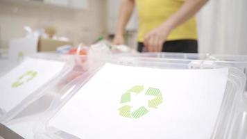 Nahansicht Recycling. im das Haus. das Person Wer Sorten es mit Kisten trennt das Reste und recycelt ihnen. es trennt Plastik, Papier und Glas. video