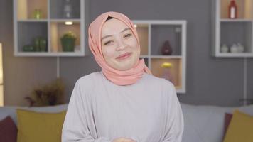 femme dans hijab souriant à caméra. femme dans foulard agitant et souriant à caméra. video