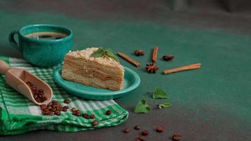 delicioso Napoleón pastel con crema en un turquesa plato decorado con un puntilla de menta en un verde antecedentes. un taza de caliente café, canela palo, badyan, café frijoles en un verde antecedentes video