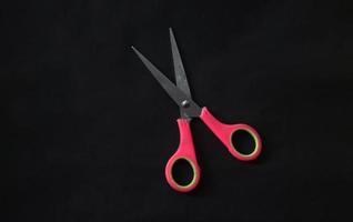 Open one single pink scissors school and office tool supplies photo isolated on plain black background.