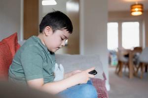 Kid using mobile phones typing text message,School Boy using cell phone searching information on internet for homework,E-learning education,Child with technology and social networking concept photo
