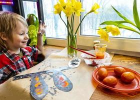boy drawing the ears of a handmade Easter bunny made of cardboard. Preparation for the celebration of the Easter holiday. photo