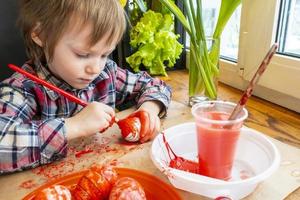 The child preparing for Easter. Paint eggs. Red paint egg. photo