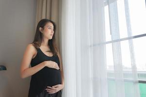 retrato de asiático embarazada mujer en el dormitorio foto