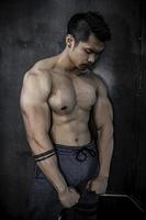 retrato de hombre asiático con gran músculo en el gimnasio, gente de tailandia, entrenamiento para una buena salud, entrenamiento de peso corporal, fitness en el concepto de gimnasio foto