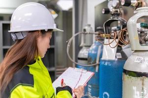 ingeniero asiático que trabaja en la sala de operaciones, la gente de tailandia usa casco, trabajó con diligencia y paciencia, revisó el regulador de la válvula en el tanque de hidrógeno. foto