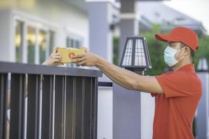 asiático entrega hombre vestir protector máscara en rojo uniforme, en línea comida y producto entrega concepto,nuevo normal en covid-19 foto