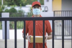 Asian Delivery  man wear protective mask in red uniform,Online food and product delivery concept,New normal in covid-19 photo