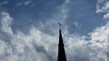 a Cruz em a cúpula do a católico têmpora, igreja, contra a fundo do flutuando branco nuvens. a tema é religião. video