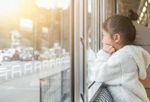 Little girl looking through window. She travels on a train. photo