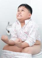 grasa chico sentado en el baño. foto