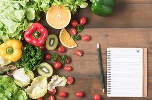 Fresh salad vegetables and fruit on wood background. photo