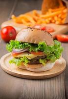 Delicious hamburger and french fries on wooden background photo