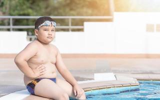 obese boy sitting in swimming pool photo