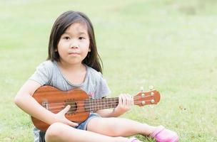 linda asiático niña jugar ukelele foto