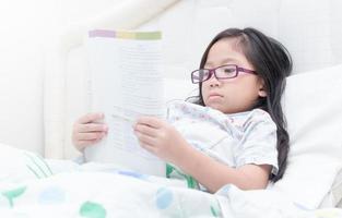 cute girl reading book on bed photo