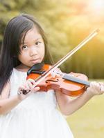 linda asiático niña jugar violín foto