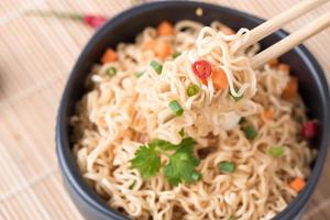 Instant noodles with vegetables on chopstick photo