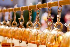 de cerca y cosecha grupo de pequeño dorado campanas colgar en tailandés templo en borroso antecedentes. foto