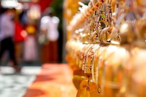 de cerca y perspectiva ver grupo de pequeño dorado campanas colgar en tailandés templo en borroso antecedentes. foto