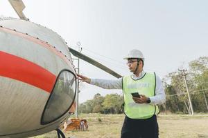 asiático melena aero ingeniero trabajando en helicóptero en hangar foto