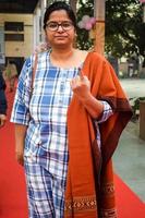 New Delhi, India - December 04 2022 - Unidentified people showing their ink-marked fingers after casting votes in front of polling booth of east Delhi area for MCD local body Elections 2022 photo