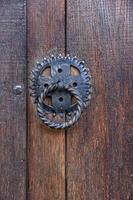 Door knocker. Old antique metal knocker on the wooden doors for knocking. Close up photo