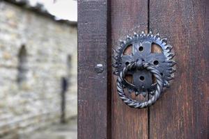 Front wooden door with a knocker, open to blur an inside yard photo