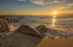 Sunrise over the sea with wave splashing on the rocks. photo