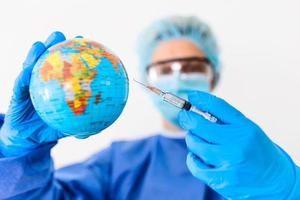 Pandemic concept, close up of scientist injecitng vaccine into the earth photo