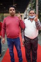 New Delhi, India - December 04 2022 - Unidentified people showing their ink-marked fingers after casting votes in front of polling booth of east Delhi area for MCD local body Elections 2022 photo
