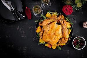 Baked turkey or chicken. The Christmas table is served with a turkey, decorated with bright tinsel. Fried chicken. Table setting. Christmas dinner. Top view photo