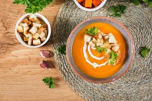 Pumpkin soup in a bowl served with parsley and croutons. Vegan soup. Thanksgiving day food. Halloween meal. Top view photo