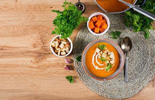 Pumpkin soup in a bowl served with parsley and croutons. Vegan soup. Thanksgiving day food. Halloween meal. Top view photo